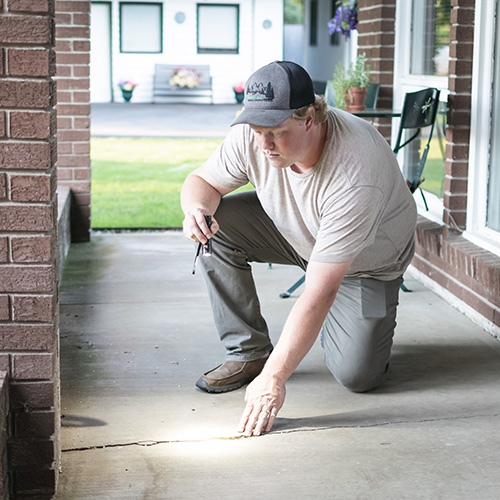 Nathan inspecting exterior foundation cracks
